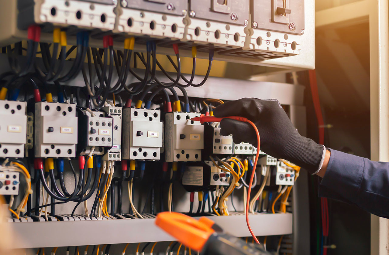 électricien vérifiant un tableau électrique avec des gants de protection