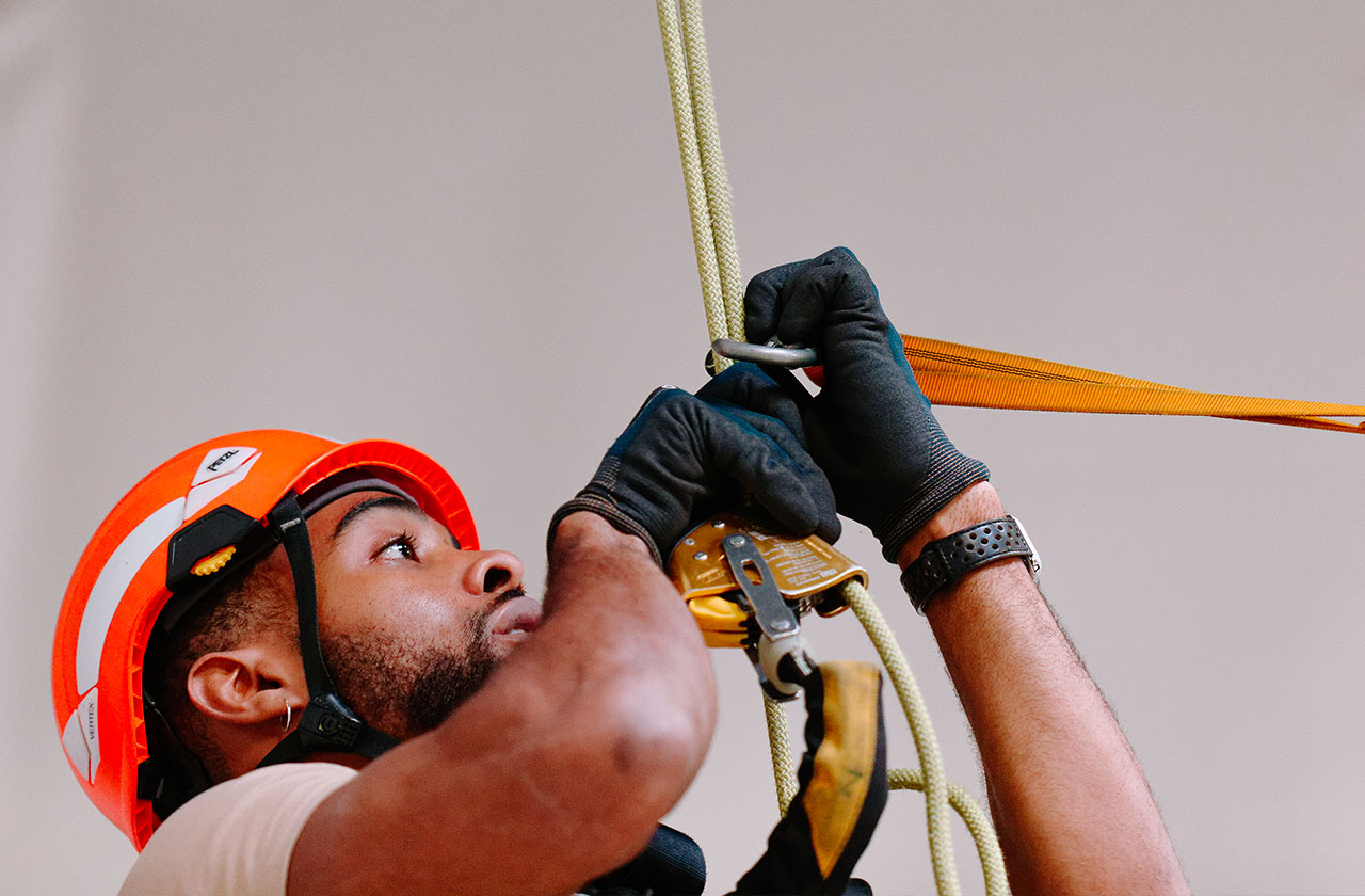 travailleur en hauteur fixant un système de corde avec casque et gants de sécurité